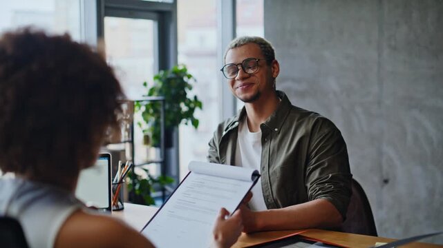 Job interview office meeting, recruiter reviewing resume with male candidate