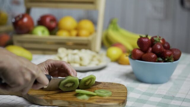 Kiwis being cut with sharp knife on cutting board - closeup shot