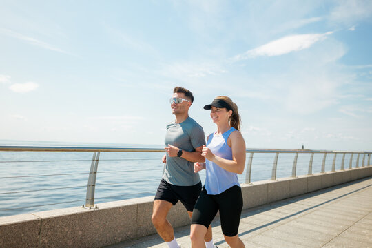 Couple enjoys a bright morning jog along the waterfront promenade under a clear sky