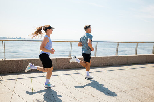 Couple enjoys a sunny morning jog along the waterfront promenade by the city skyline