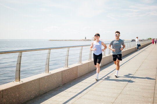 Morning joggers share smiles along the vibrant waterfront pathway under a clear blue sky