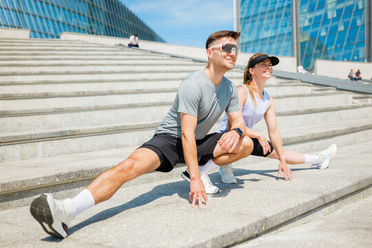 Stretching together on sunny steps in an urban landscape, enjoying fitness and friendship