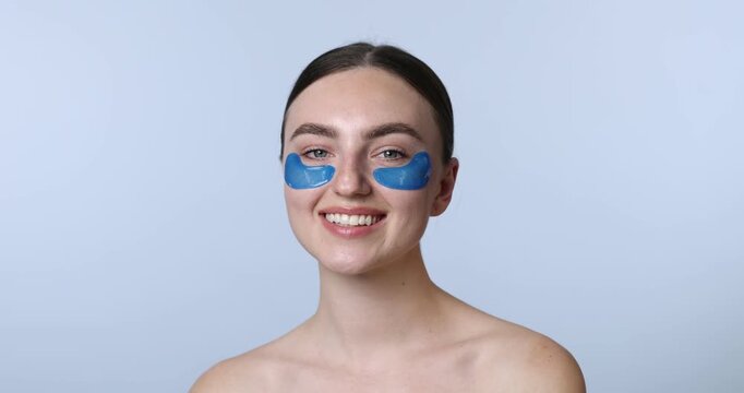 Beautiful woman with eye patches on light blue background
