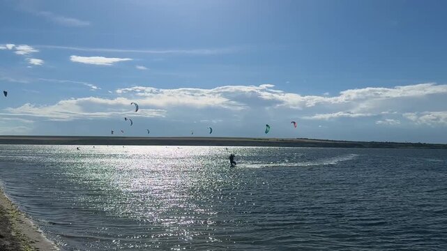 People kitesurfing on sea during sunny day