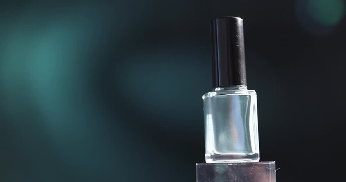 Nail polish in bottle on podium against dark background, closeup. Camera moving left