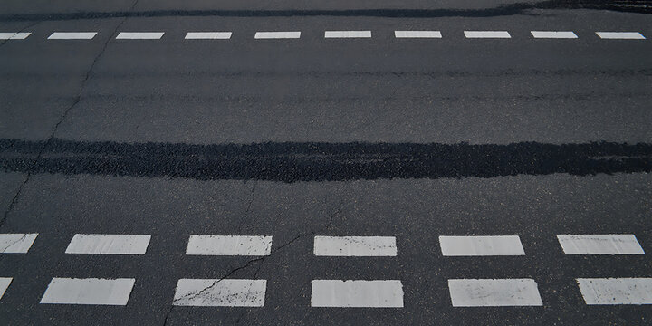 Asphalt road surface with white dashed lane markings and a dark wet patch transparent