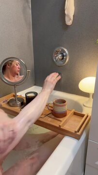 woman lathering deep cleansing oil on her body in the bath