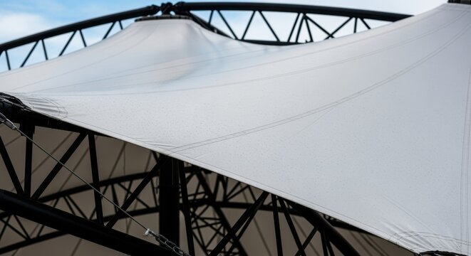 Closeup details of the fabric membrane stretching across steel framework during concert roof deployment highlighting texture and tensile architecture.
