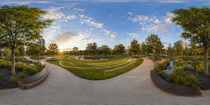 HDRI Contemporary City Park 360 Panoramic view of an urban green space with tiled walkways, landscaped lawns, shaded seating, and modern buildings beneath a bright blue sky