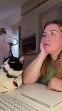 tired woman working at her computer with a supportive cat next to her