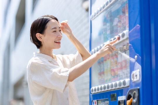 自動販売機で飲み物を買う女性