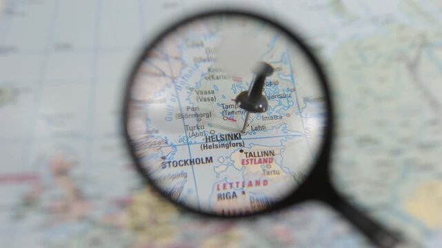 Magnifying glass focuses on Helsinki on a paper map of Europe