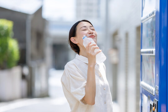 水を飲む女性　自動販売機