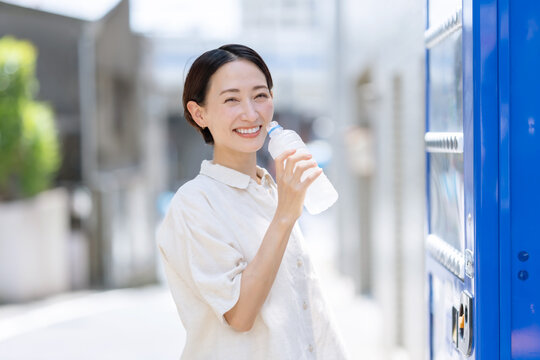 水を飲む女性　自動販売機