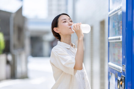 水を飲む女性　自動販売機