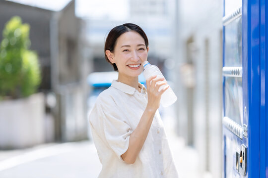水を飲む女性　自動販売機