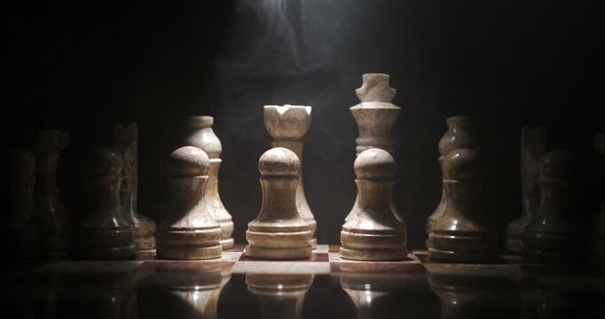 Chess pieces arranged on a board with dramatic lighting in a dark setting