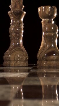 Chess pieces on a marble board with reflections in dim lighting