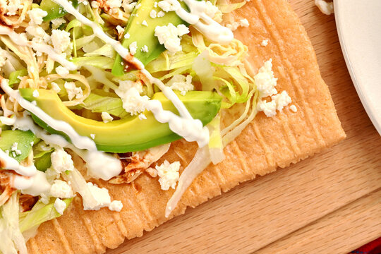 Top view of chicharron prepared with lettuce, shredded chicken, sour cream, cheese and red sauce, traditional Mexican cuisine and street food