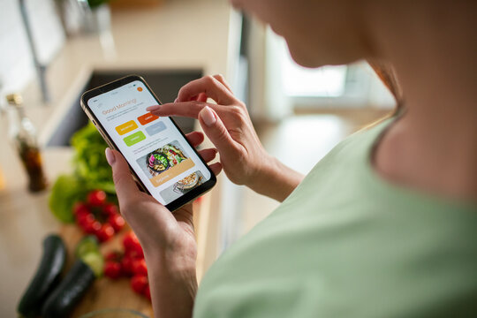Person using meal planning app on smartphone in home kitchen