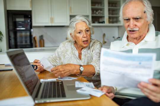 Senior couple reviewing household bills at kitchen table