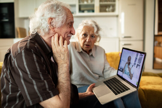 Elderly couple consulting doctor via laptop at home