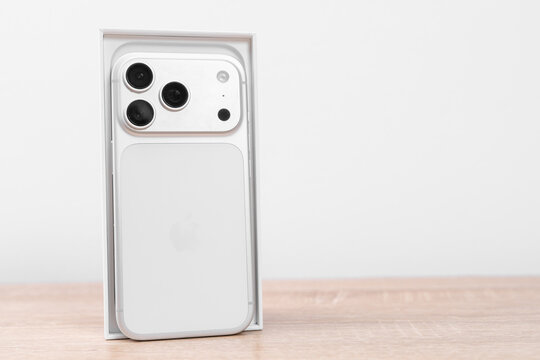 Bar, Montenegro: February 6, 2026: White apple iphone 17 pro standing in open retail box on wooden table against soft grey wall, new device launch delivery concept