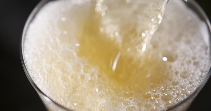 Slow motion pouring of beer into a glass with bubbles and foam