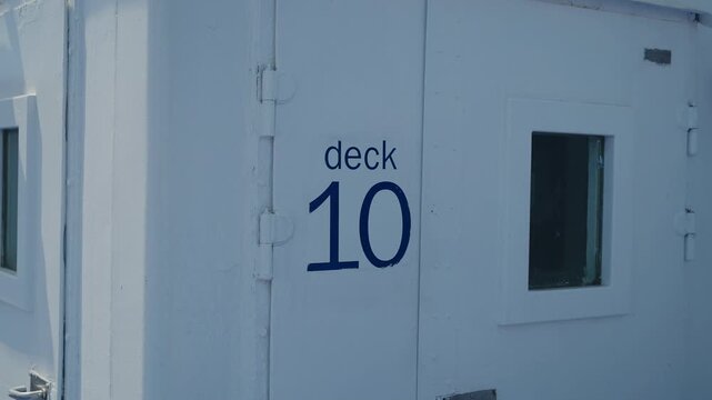 Blue deck 10 lettering painted on white metal wall of ferry ship exterior
