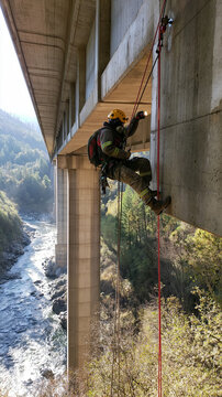 Rope rescue bridge inspection with safety harness climber rappelling outdoors river during emergency services training