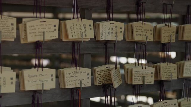 Rows of handwritten wooden ema prayer plaques hanging on a rack at a Shinto shrine in Japan