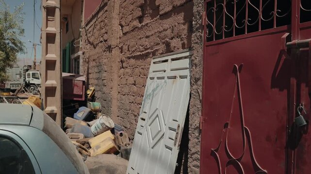 Building debris and an old door piled by a mud brick wall in a rural Morocco street