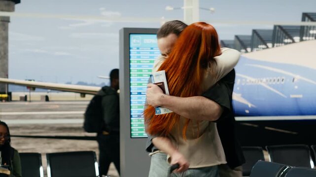 A young couple hugs tightly during an emotional farewell at an airport gate, capturing sadness as the man leaves for relocation and the woman stays behind before an international flight.