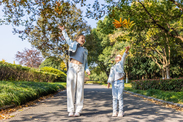 Fototapeta premium kids throwing autumn leaves in a sunny park