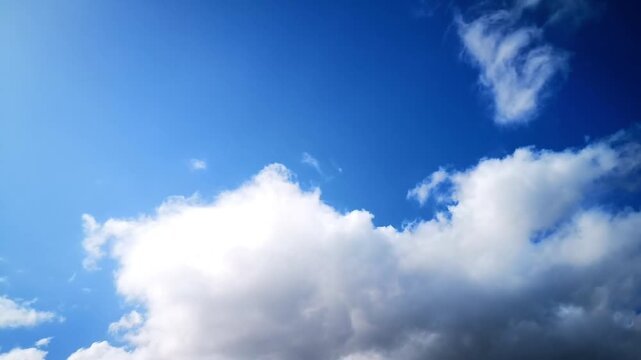 Beautiful view of a bright blue sky sprinkled with altocumulus clouds that form unique fiber and wave patterns. There are also a few white clouds (cumulus) in the lower corner that are moving slowly.