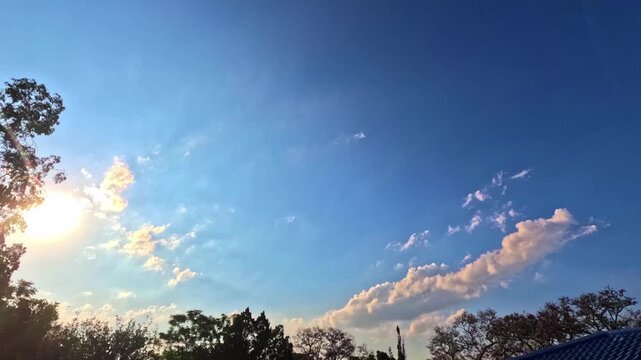 A captivating blue sky scene in the late afternoon, revealing the gentle movement of clouds and crepuscular rays radiating beautifully from behind them.