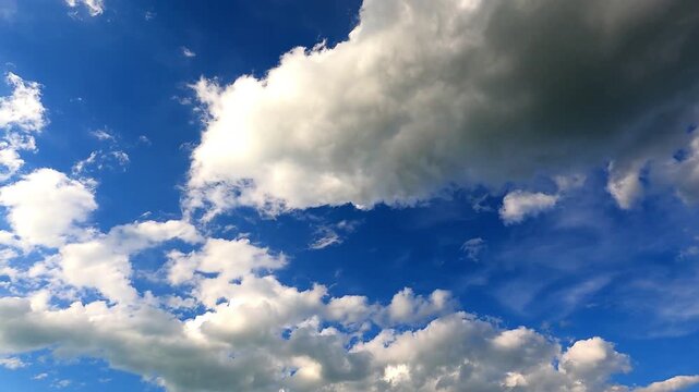 the view of a bright blue sky filled with wisps of white clouds (cumulus) floating and moving slowly. Bright natural lighting creates a calm, fresh and peaceful atmosphere,