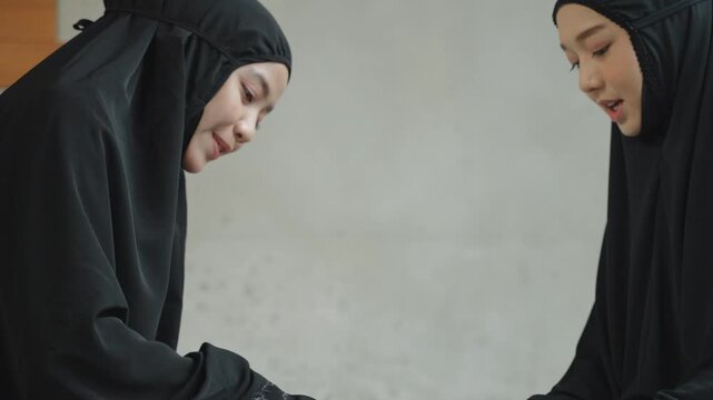 Two Muslim women studying the Quran together while sharing ideas and learning from religious scripture. Islamic education, friendship, faith, and lifelong learning concept.
