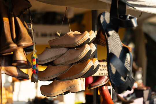 Traditional handmade wooden clogs hanging at an outdoor market stall