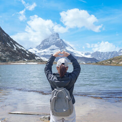 Fototapeta premium Woman Tourist Exploring Zermatt, Switzerland. Traveler Making Heart Shape with Hands at Riffelsee Lake and Matterhorn, Famous European Landmark, Hiking Attraction, Travel Destination in Europe