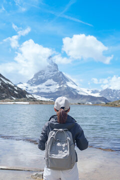 Woman Tourist Exploring Zermatt, Switzerland. happy hiker sightseeing iconic Matterhorn Swiss Alps at Riffelsee Lake, Famous European Landmark, Hiking Attraction and Travel Destination in Europe