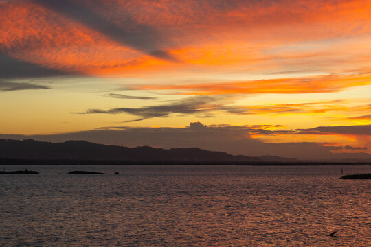 Vibrant Sunset Over Calm Water and Distant Mountains