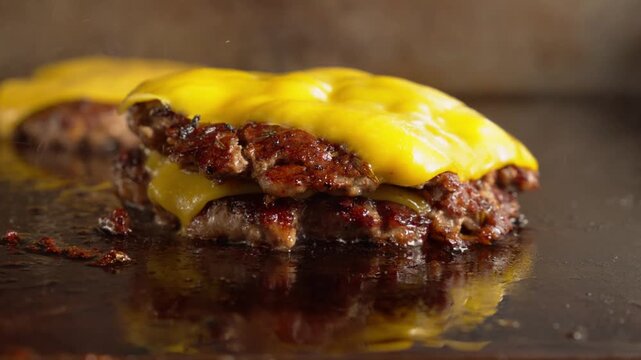 Double cheeseburger assembly, stacking Melted cheese burger patties on griddle, close up