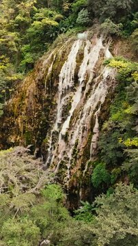 La Gloria Tolantongo hot spring waterfall cascading over mineral rock formations surrounded by lush tropical vegetation in the famous Grutas de Tolantongo canyon, Hidalgo, Mexico