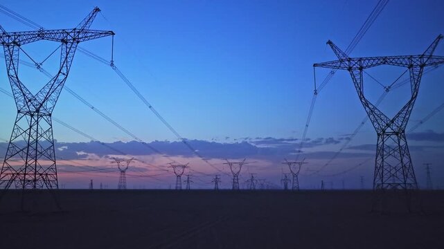 High-voltage power transmission tower at dusk