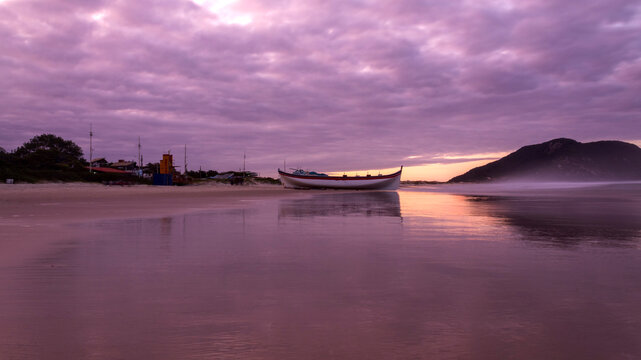 Pesca da tainha em Florianopolis p&ocirc;r-do-sol com nuvens carregadas de chuva e o barco ancorado e um carro passando na areia da praia do Santinho Ingleses ilha de Florian&oacute;polis Santa Catarina Brasil 