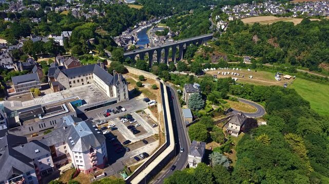 Drone pull-back revealing the Rance Valley, the Dinan Viaduct, surrounding farmland, roads and part of the historic town of Dinan in Brittany, France.