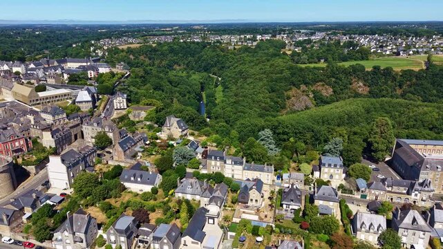 Forward drone flight above Dinan revealing the Rance Valley, historic neighborhoods, wooded hillsides and the surrounding landscape in Brittany, France.