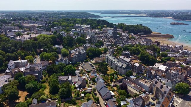 Drone flies above Sainte Croix Church with the Rance estuary in Saint-Malo, France.