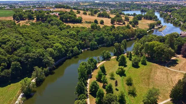 Drone flying above the winding Mayenne River through forests and farmland in western France.